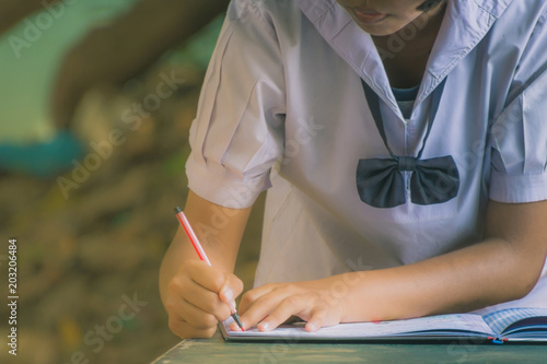 Female student write a notebook for graduates in secondary schoo