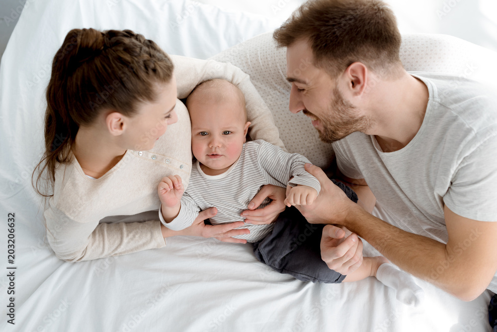 overhead view of happy family with little son lying on bed