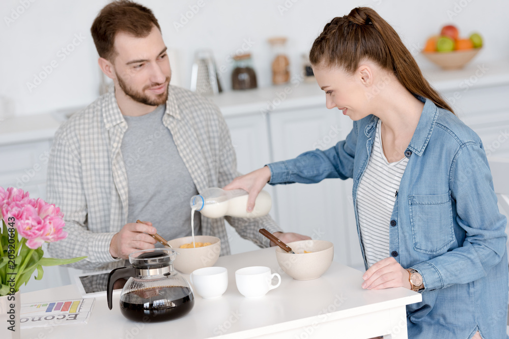 young couple having breakfast with corn flakes and coffee young couple having breakfast with corn flakes and coffee