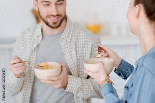 young couple eating corn flakes for breakfast