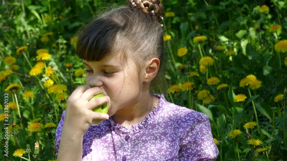 Young beautiful girl eats an apple on nature. The health of our children. Healthy food and organic fruits and food. Young beautiful girl eats an apple on nature. The health of our children. Healthy food and organic fruits and food.