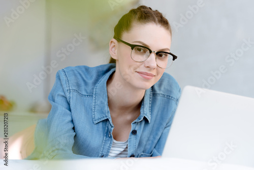 attractive young woman in eyeglasses using laptop