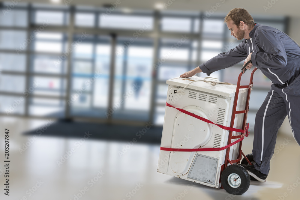 Delivery man pushing hand truck washing machine home appliance Stock