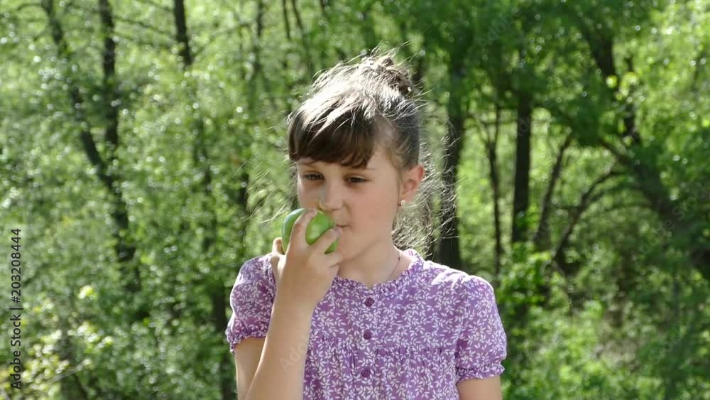 Young beautiful girl eats an apple on nature. The health of our children. Healthy food and organic fruits and food. Young beautiful girl eats an apple on nature. The health of our children. Healthy food and organic fruits and food.