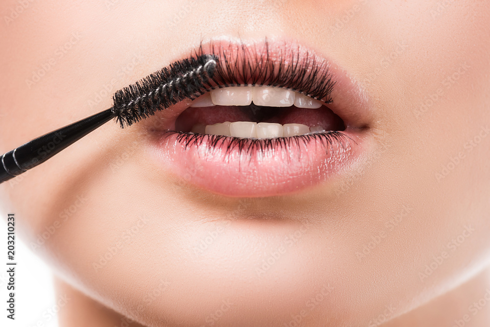 cropped image of woman applying mascara on eyelashes on lips isolated on white