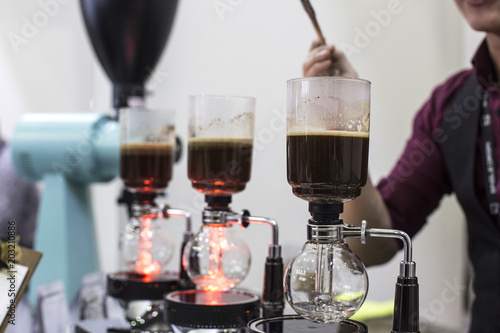 coffee preparation step by step. extraction process. Barista is pouring siphon into the flask from the kettle of hot water