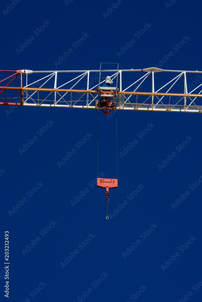 Red hook suspended from a construction crane, against a blue sky
