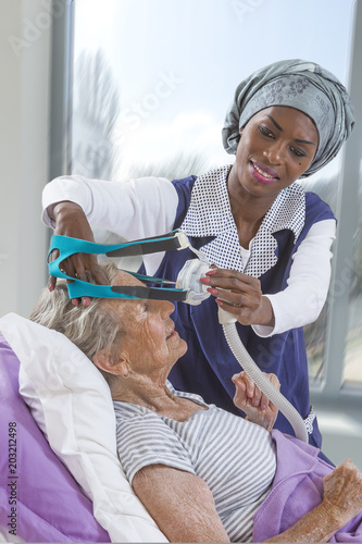 care giver Adjusting CPAP machine to an elderly woman at home