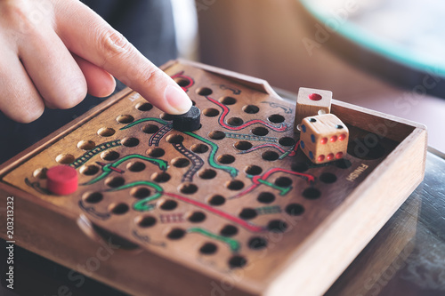 Closeup image of a hand playing wooden Snakes and Ladders game