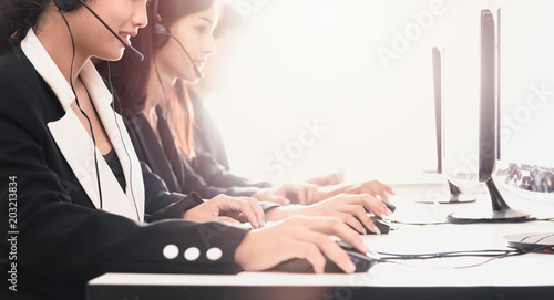 Young beautiful employees working with a set of headphones with she's contact to help in the proposition to customer service agents on in a call center.