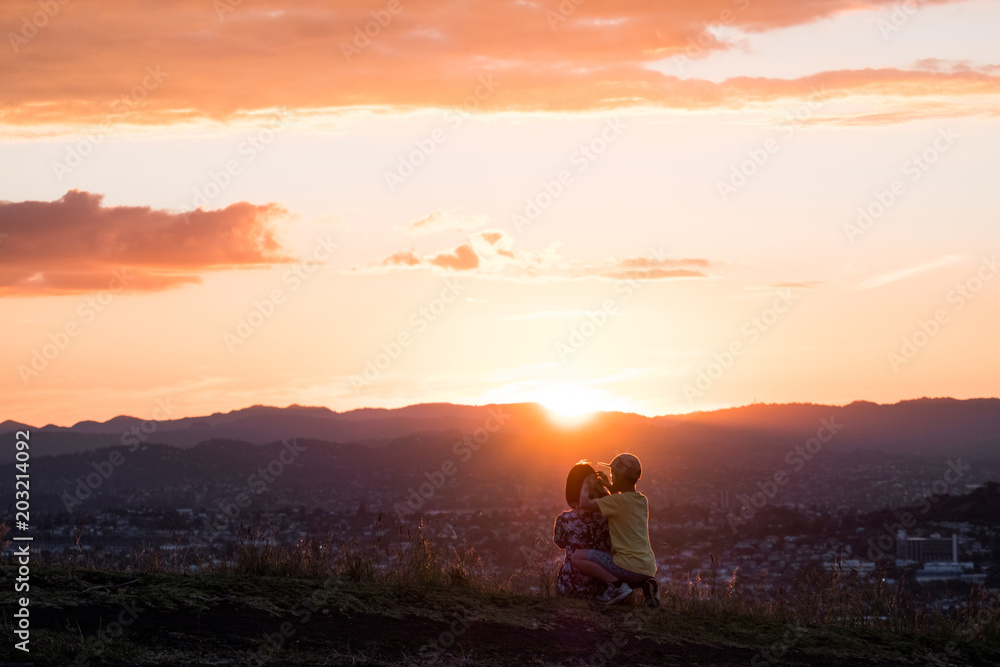 Mom and son enjoy together their sunset over the mountain and the town.