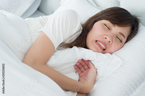 stressed woman with grinding teeth, bruxism symptoms; portrait of stressful, exhausted, tired sleeping woman grinding her teeth with stress; oral, dental care medical concept; asian adult woman model
