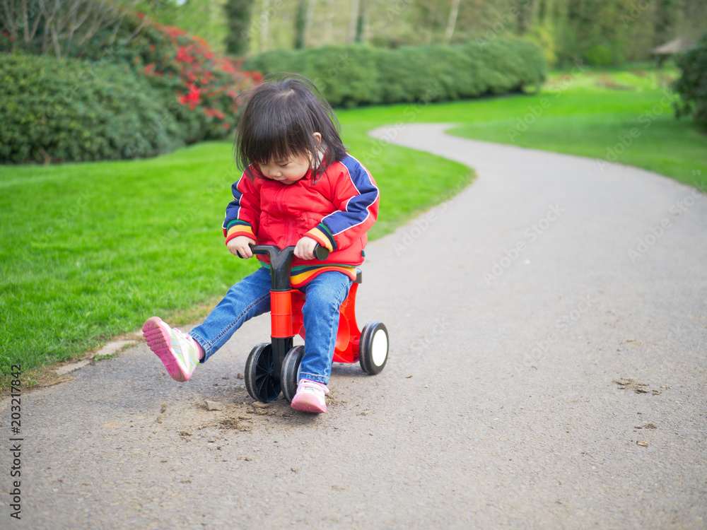 Baby girl play bicycle at outdoor playground