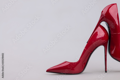 Φωτογραφία Close-up of red patent leather high heel shoes on light background, side view, fashion footwear concept