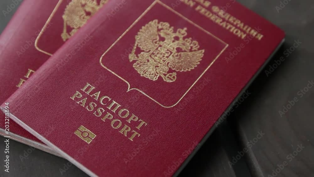 Male hand puts two international passports on wooden background. Closeup Male hand puts two international passports on wooden background. Closeup