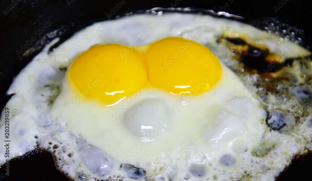 Fried one egg with two yolks. Strange phenomenon. Breakfast in a cast iron pan. Fried one egg with two yolks. Strange phenomenon. Breakfast in a cast iron pan.