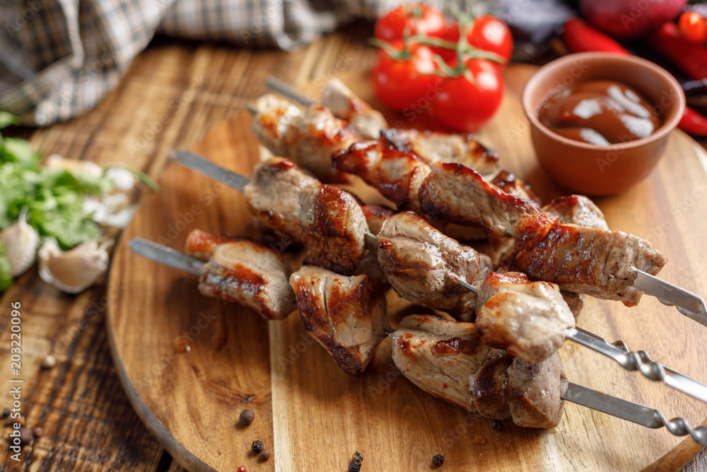 Juicy kebabs of pork and fresh vegetables on a wooden background. Meat cooked on an open fire. Rustic.