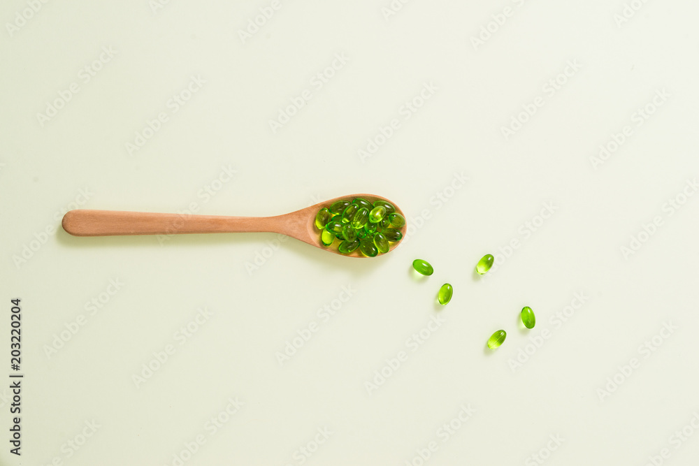 Εκτύπωση καμβά Close up of green softgel capsules with wooden spoon on isolated white background