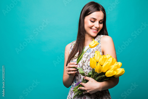 Birthday present. Beautiful girl in the dress counting flowers tulips in hands on a blue background photo