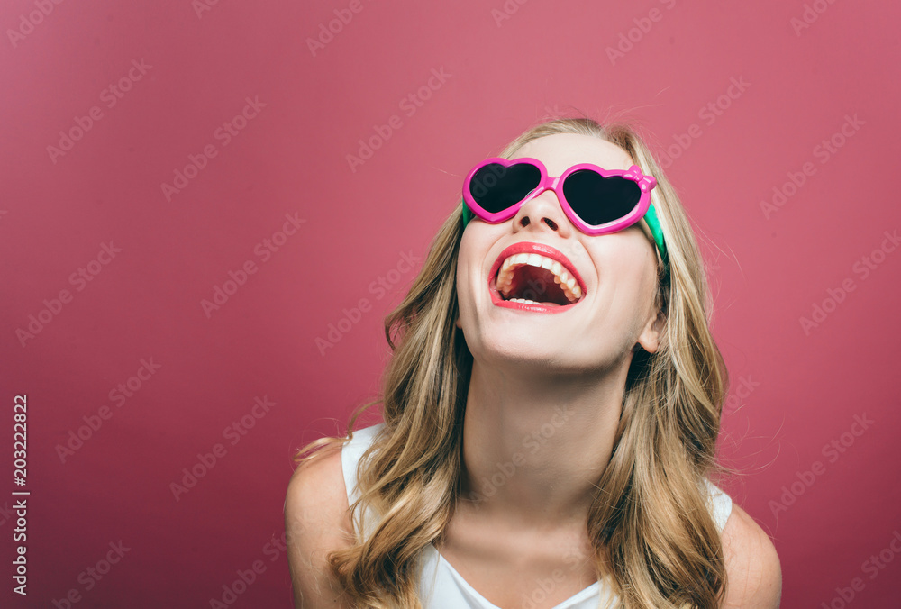 A portrait of a girl that wars glasses. She is smiling and looking up. Girl is very cheerful. Isolated on pink background. A portrait of a girl that wars glasses. She is smiling and looking up. Girl is very cheerful. Isolated on pink background.