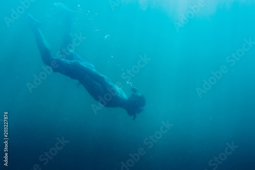 Young man free diver swimming in deep sea.