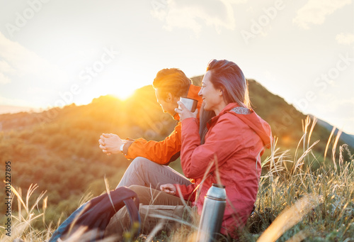 Happy traveler couple resting in the mountains at sunset.