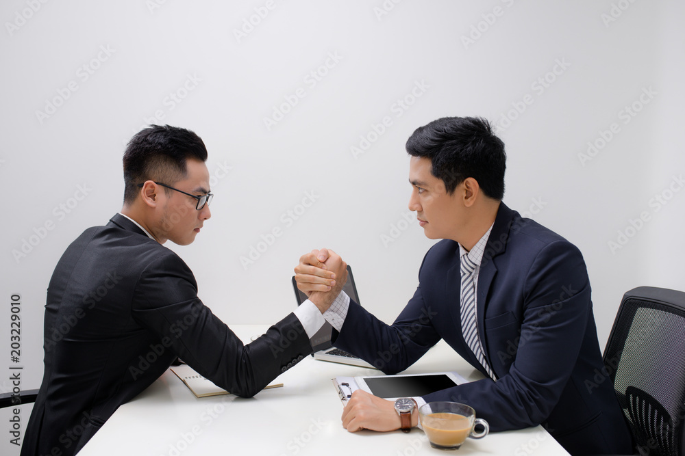 Two businessmen competing arm wrestling in office Two businessmen competing arm wrestling in office
