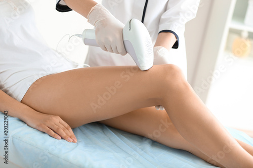 Woman undergoing hair removal procedure with photo epilator in salon