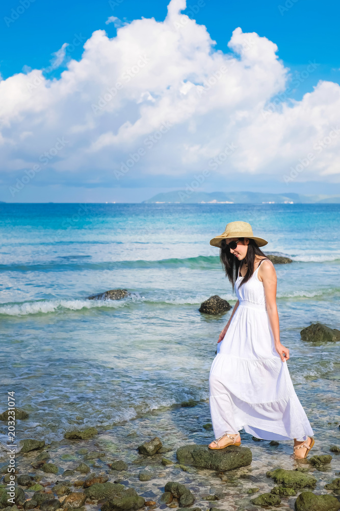 woman traveler enjoying for view of the sea on her holiday.beautiful Asia Lady tourist in white dress and rise walking on the beach. woman traveler enjoying for view of the sea on her holiday.beautiful Asia Lady tourist in white dress and rise walking on the beach.