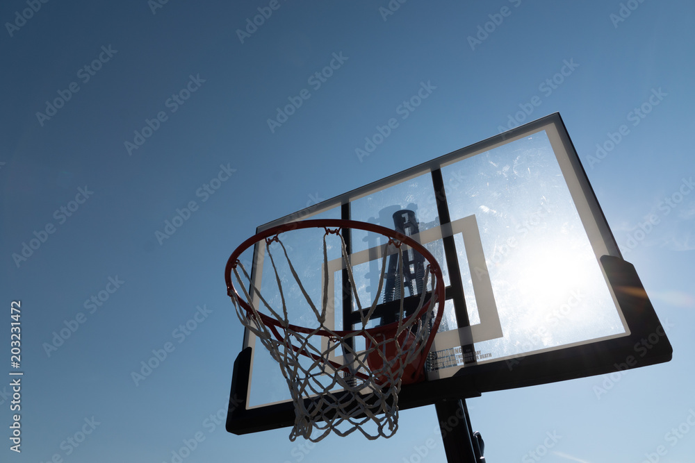 Basketball hoop photographed from below on a beautiful summer day wth sun flair