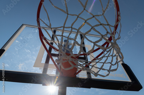 Basketball hoop photographed from below on a beautiful summer day with sun flair
