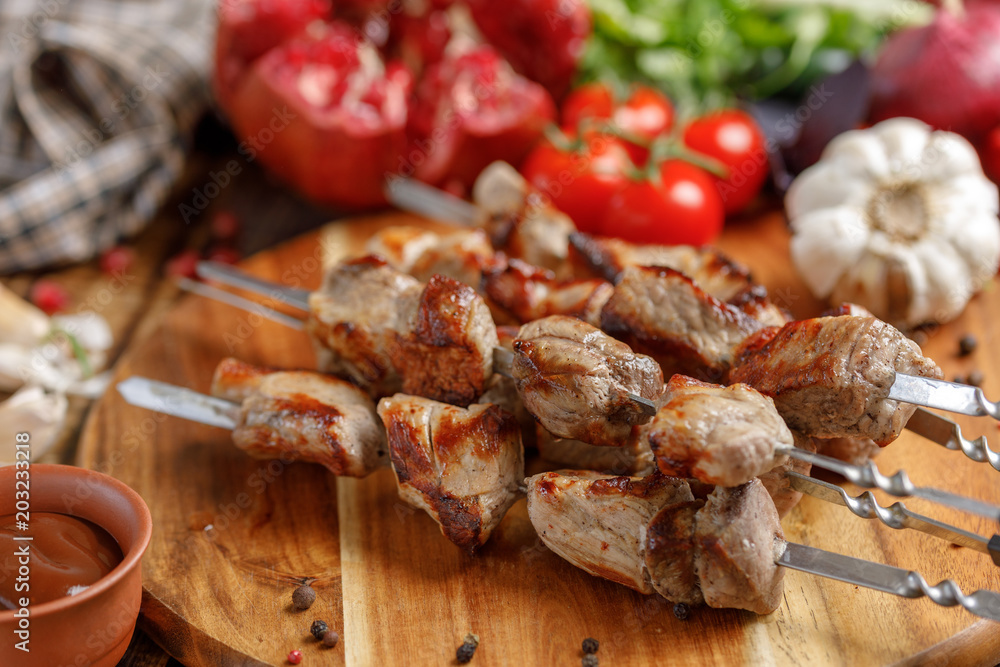 Juicy appetizing shish kebabs cooked on an open fire. Still life with textiles on a wooden background. Juicy appetizing shish kebabs cooked on an open fire. Still life with textiles on a wooden background.