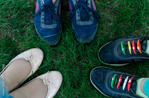 Three people are standing on green grass opposite each other shod in ballet flats and sneakers