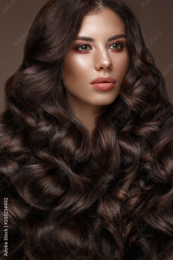 Beautiful brunette model with curls, classic makeup and full lips. The beauty of the face. Portrait shot in the studio. Beautiful brunette model with curls, classic makeup and full lips. The beauty of the face. Portrait shot in the studio.