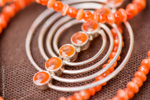 Serdolik (carnelian) stone necklace laying on natural brown linen tablecloth. Yashma, orange jasper, onyx gemstones around. Healing, powerful energy for crystal therapy treatments. Esoteric background photo