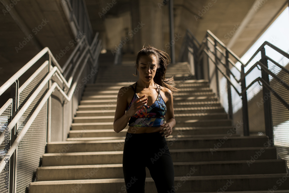 Fototapeta premium Young woman running alone down stairs