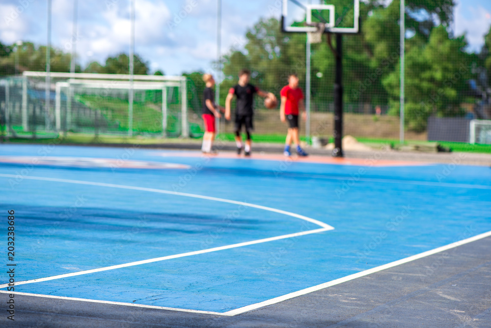 Naklejka premium Abstract, blurry background of boys playing basketball in outdoor basketball court in park