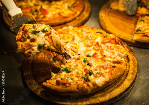 pickup pizza by pizza lap,eating hawaiian pizza,pizza put on wooden plate with warm light,peanut pizza lay on wooden plate