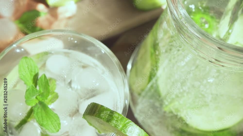 Leaves of mint in water with bubbles in a decanter with cucumbers and a glass with a drink slow motion Leaves of mint in water with bubbles in a decanter with cucumbers and a glass with a drink slow motion