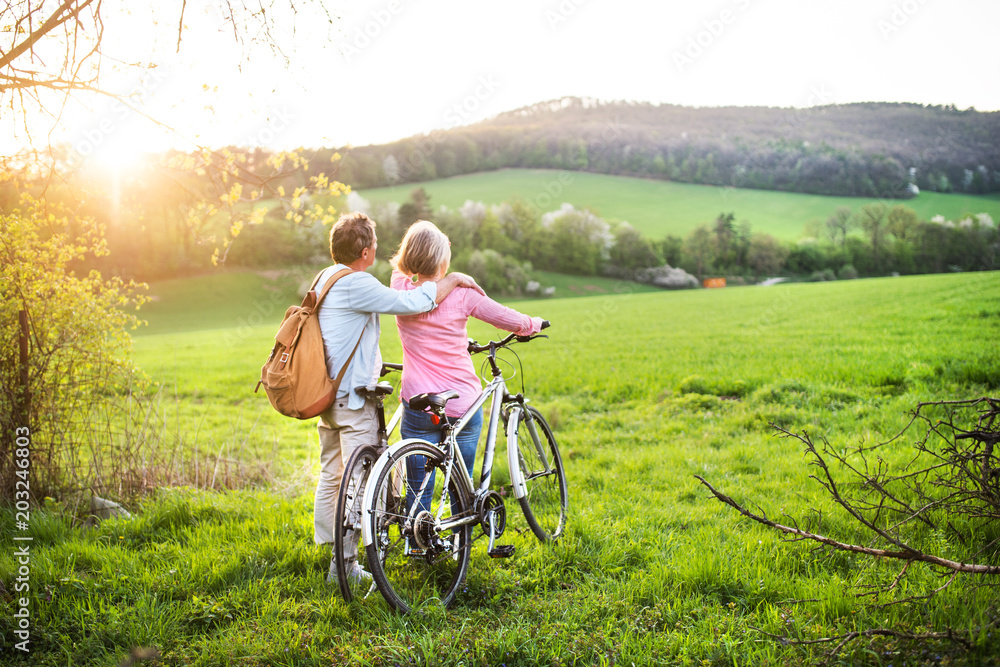 Fototapeta premium Beautiful senior couple with bicycles outside in spring nature.