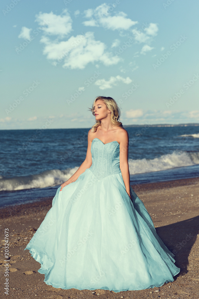 woman in blue tulle dress enjoying sun on beach woman in blue tulle dress enjoying sun on beach
