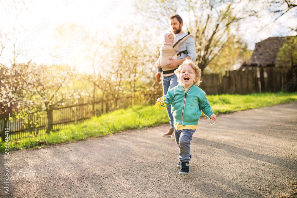 Fototapeta premium A father with his toddler children outside on a spring walk.