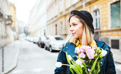 Young woman with flowers in sunny spring town.