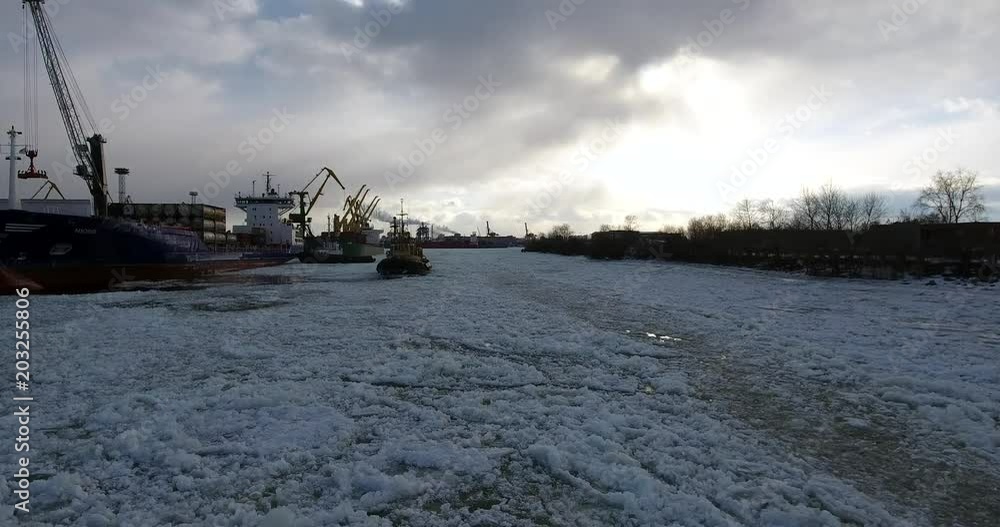 Flying over cargo port. The tugboat moving through an ice. Aerial drone footage Flying over cargo port. The tugboat moving through an ice. Aerial drone footage