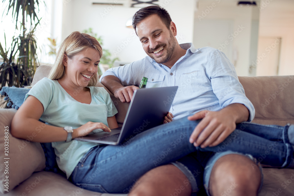 Young couple sitting in the living room and using laptop. Young couple sitting in the living room and using laptop.