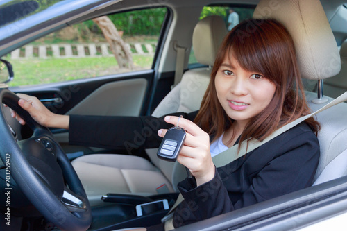 Smiling businesswoman giving a car key while in the car - business concept