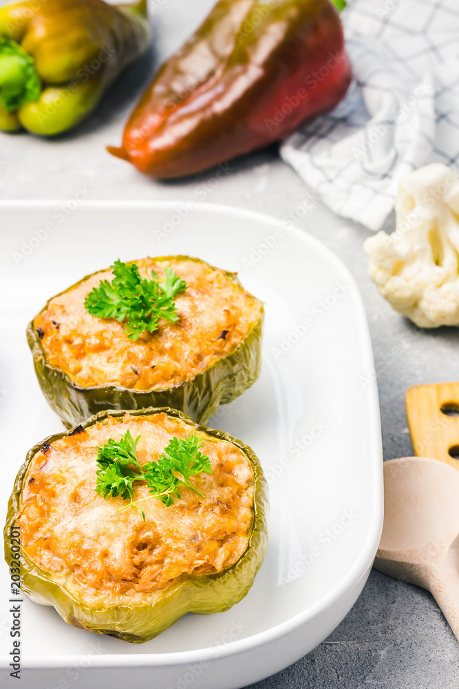 Chicken alfredo stuffed peppers in baking dish on light concrete background. Selective focus, copy space. Chicken alfredo stuffed peppers in baking dish on light concrete background. Selective focus, copy space.