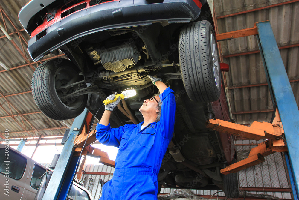 custom made wallpaper toronto digitalCar mechanic examining car using flashlight in auto repair service.