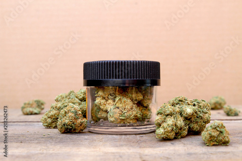 Marijuana in Jar Surrounded by Buds on Table (Green Crack, Sativa Dominant Hybrid Strain) photo