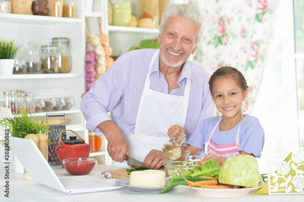 Senior man with granddaughter preparing dinner in kitchen